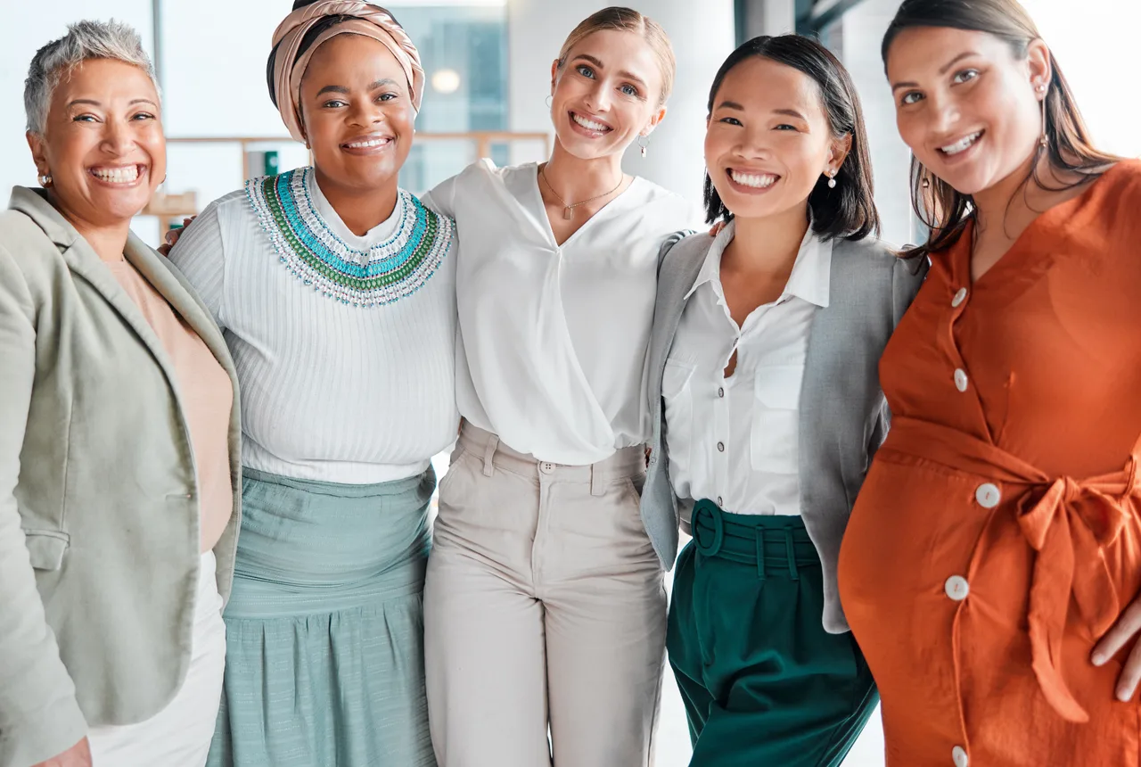 A group of five diverse women of different ages smiling together